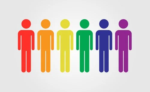 Seis figuras em formato de palito, em tons crescentes de vermelho, laranja, amarelo, verde, azul e roxo, estão alinhadas contra um fundo simples, muito semelhantes à diversidade vibrante que se pode encontrar numa viagem colorida ao Dubai.