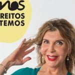 Uma mulher de cabelo comprido e batom vermelho sorri, tocando no cabelo com as duas mãos. No texto da imagem lê-se "SOMOS OS DIREITOS QUE TEMOS" em português, incorporando o espírito de resiliência face aos preconceitos em Portugal.