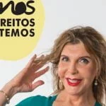 Uma mulher de cabelo comprido e batom vermelho sorri, tocando no cabelo com as duas mãos. No texto da imagem lê-se "SOMOS OS DIREITOS QUE TEMOS" em português, incorporando o espírito de resiliência face aos preconceitos em Portugal.