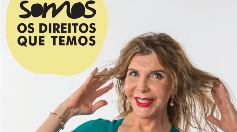 Uma mulher de cabelo comprido e batom vermelho sorri, tocando no cabelo com as duas mãos. No texto da imagem lê-se "SOMOS OS DIREITOS QUE TEMOS" em português, incorporando o espírito de resiliência face aos preconceitos em Portugal.