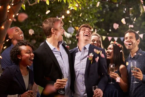 Pedro, um rapaz normal, está entre um grupo de pessoas trajadas formalmente a rir e a celebrar sob luzes decorativas. Taças de champanhe tilintam enquanto as flores caem graciosamente à volta delas, criando uma atmosfera mágica na noite alegre.
