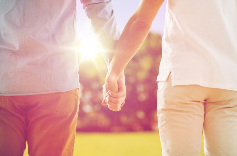 Duas pessoas dão as mãos enquanto caminham ao ar livre, com a luz do sol a brilhar por entre os seus braços, o que me faz lembrar os passeios que costumava dar com o meu pai.