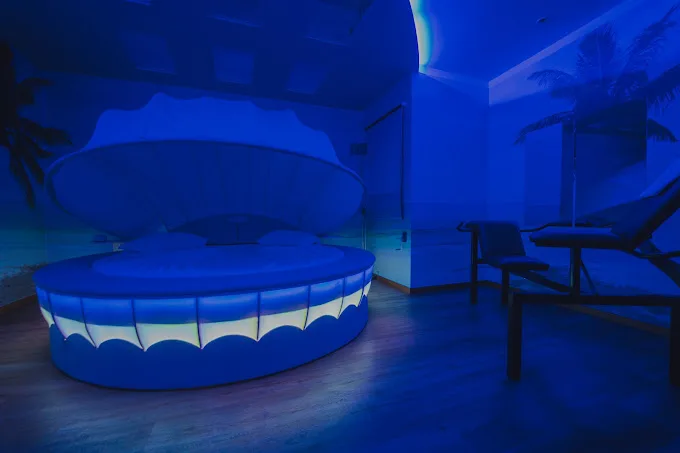 Quarto no D'Lirius Azuis Um quarto iluminado por luz azul, com uma grande cama em forma de concha